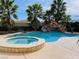 Backyard pool and hot tub with a cascading waterfall and lush palm trees, creating a private oasis at 12283 Lost Treasure Ave, Las Vegas, NV 89138