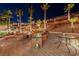 Outdoor kitchen and seating area in the backyard with palm trees at night at 2064 Poetry Ave, Henderson, NV 89052