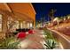 Covered patio with dining set overlooking a landscaped backyard with tiered retaining walls and palm trees at 2064 Poetry Ave, Henderson, NV 89052