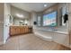 Bathroom showcasing a tub under windows, dual sinks, and tile floors, offering style and comfort at 2064 Poetry Ave, Henderson, NV 89052