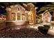 Inviting home exterior with arched entryway, stone accents, manicured landscaping, and warm lighting at 2064 Poetry Ave, Henderson, NV 89052