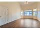 Bedroom with wood floors, three windows, ceiling fan and a door to a hallway at 225 Deer Crossing Way, Henderson, NV 89012