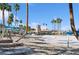 Community beach area with lounge chairs, blue shade canopies, and palm trees creating a relaxing retreat at 2632 Starfish Ct, Las Vegas, NV 89128