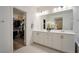 Luxurious bathroom with double sinks, white cabinets, and a walk-in closet for ample storage at 27 Parco Fiore Ct, Henderson, NV 89011