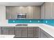 Bright kitchen featuring ample counter space, gray cabinets, and a stylish blue tile backsplash at 6033 Torciano St, North Las Vegas, NV 89081