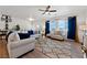 Bright living room features a ceiling fan, large windows with beautiful blue curtains, and stylish, modern furniture at 6101 Cavalry Trl, Pahrump, NV 89060