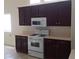 Kitchen featuring modern white appliances, dark wood cabinets, and laminate countertops at 6119 Magic Mesa St, North Las Vegas, NV 89031
