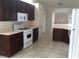 Well-lit kitchen with tile flooring, dark wood cabinetry, and white appliances at 6119 Magic Mesa St, North Las Vegas, NV 89031