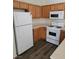 Kitchen featuring white appliances, wood cabinetry, and vinyl flooring at 6425 Extreme Shear Ave # 101, Henderson, NV 89011