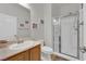 Clean and modern bathroom with a glass-enclosed shower, wooden vanity, and decorative wall art at 765 Crimson Peak Pl, Henderson, NV 89011
