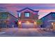 Two-story home with a brick driveway and a two-car garage, beautifully lit at twilight at 765 Crimson Peak Pl, Henderson, NV 89011
