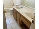 Bathroom featuring double sinks, wood vanity, tile floors and white tub and toilet at 7732 Blackbird Ave, Las Vegas, NV 89145