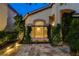 Attractive exterior with tan stucco, a large bay window, landscaped greenery, stone tile patio and warm exterior lighting at 812 Eaglewood Dr, Las Vegas, NV 89144