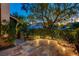 Lush front yard featuring a stone-paved patio, mature trees, and a wrought iron gate at 812 Eaglewood Dr, Las Vegas, NV 89144