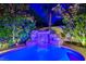 Backyard pool featuring custom rock waterfall surrounded by meticulously maintained landscaping and outdoor lighting at 812 Eaglewood Dr, Las Vegas, NV 89144