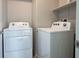 Bright laundry room with a white washer and dryer set, complemented by a shelf for storage at 9871 Magnus Ct, Las Vegas, NV 89178