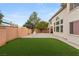 Spacious backyard featuring an artificial lawn, a brick perimeter wall, and mature trees at 10501 Haywood Dr, Las Vegas, NV 89135