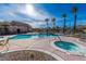 Community pool with hot tub, tables, chairs, and tall palm trees with clear blue skies in the background at 10633 Tinta Ln, Las Vegas, NV 89144