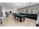 Spacious living room featuring a pool table, a comfortable sofa, and large windows that let in natural light at 10725 Bernini Dr, Las Vegas, NV 89141