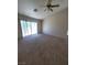 Bright bedroom with neutral carpeting, a ceiling fan, and a sliding glass door leading to the backyard at 1540 Sabatini Dr, Henderson, NV 89052