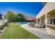 Spacious backyard with artificial turf, pool, outdoor dining area, and lush landscaping, perfect for entertaining at 165 Inveraray Ct, Henderson, NV 89074