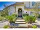 Inviting front entrance with an arched doorway, stone steps, and lush, mature landscaping at 165 Inveraray Ct, Henderson, NV 89074
