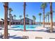 A community pool with palm trees and lounge chairs under a clear blue sky offers a resort-like setting for relaxation and recreation at 2114 Cold Canyon Ave, North Las Vegas, NV 89086