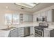 Well-lit kitchen showcases gray cabinets, white quartz countertops, stainless steel appliances, and open shelving at 2824 Dry Plains Dr, Las Vegas, NV 89134