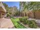 Expansive backyard with a stone fire pit, lush greenery, and well-maintained brick pathways at 3 Glendora Ct, Henderson, NV 89052
