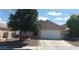 Tan single-story home with a two car garage, desert landscaping and mature shade tree in the front yard at 33 Newburg Ave, North Las Vegas, NV 89032