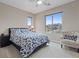A bedroom featuring a bed with floral bedding, a sitting chair, and large windows at 342 Molinetto St, Las Vegas, NV 89138