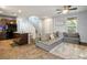 Open-concept living room featuring tile flooring and a plush grey sectional couch, bathed in natural light from a nearby window at 4610 Lime Straight Dr, Las Vegas, NV 89115