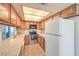 Compact kitchen with oak cabinetry, white appliances, and tile countertops at 5068 Jeffreys St # 202, Las Vegas, NV 89119