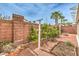 Well-maintained backyard with a brick wall, lush greenery, a gardening bed, and rock ground cover at 6843 Philharmonic Ave, Las Vegas, NV 89139