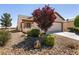 Inviting front exterior featuring desert landscaping, mature trees, and a well-maintained lawn at 7824 Pine Warbler Way, North Las Vegas, NV 89084