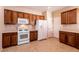 Traditional kitchen featuring wood cabinets, white appliances, and tile floors at 7824 Pine Warbler Way, North Las Vegas, NV 89084