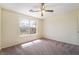 Bright bedroom with neutral carpeting, ceiling fan, and a large window providing natural light at 824 Bussora Rose Dr, Henderson, NV 89015