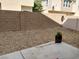 The backyard features a patio area, a gravel landscape, and a brick wall at 8664 Traveling Breeze Ave # 102, Las Vegas, NV 89178