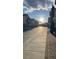 Neighborhood street view shows a sidewalk lined with townhomes at golden hour at 8664 Traveling Breeze Ave # 102, Las Vegas, NV 89178