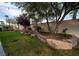 Well-manicured backyard with lush lawn, fire pit, mature trees, and a retaining wall at 8980 Tumbling Pebble Way, Las Vegas, NV 89123