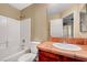 Bathroom includes tiled shower/tub, wooden vanity, large mirror and white toilet seat at 9073 Spoonbill Ridge Pl, Las Vegas, NV 89143