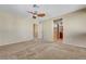 Bedroom with neutral walls, carpet, and a ceiling fan, featuring an ensuite bathroom and closet at 9073 Spoonbill Ridge Pl, Las Vegas, NV 89143