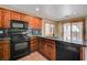An eat-in kitchen with warm wood cabinets and black appliances overlooking the backyard at 9073 Spoonbill Ridge Pl, Las Vegas, NV 89143