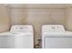 Dedicated laundry area with washer, dryer, and overhead storage shelving for organization at 9073 Spoonbill Ridge Pl, Las Vegas, NV 89143