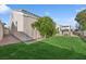 Well-maintained backyard featuring lush green grass, mature trees, a patio cover, and a spa at 9211 Golden Feather Ct, Las Vegas, NV 89147
