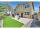 Landscaped backyard featuring artificial grass, patio, firepit, grill, and the home's exterior at 9221 Steeltree St, Las Vegas, NV 89143