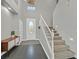 A bright and airy entryway with a staircase, gray tile floors, and neutral paint provides a calming welcome at 9221 Steeltree St, Las Vegas, NV 89143