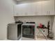 Well-lit laundry room boasts gray washer and dryer, convenient storage cabinets, and extra space for household needs at 11297 Essence Point Ave # 102, Las Vegas, NV 89135