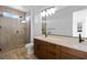 Bright bathroom features a glass enclosed shower, wood cabinets, double sinks, and a modern light fixture at 11756 Emerald Lake Ave, Las Vegas, NV 89138