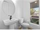 Powder room featuring a pedestal sink, modern fixtures, and a window overlooking lush greenery at 11756 Emerald Lake Ave, Las Vegas, NV 89138